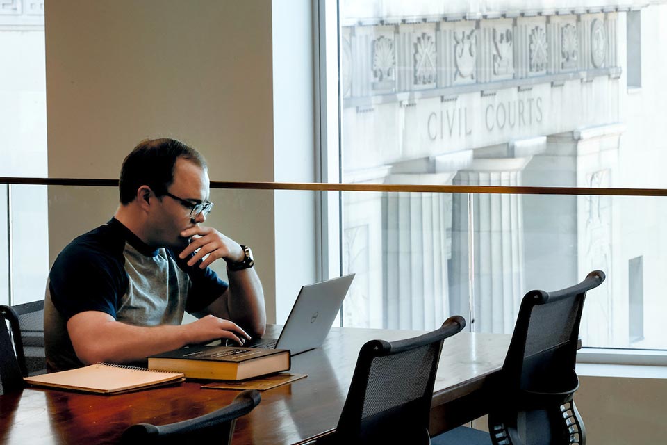 A student sits in front of a window that looks out over St. Louis city Civil Courts