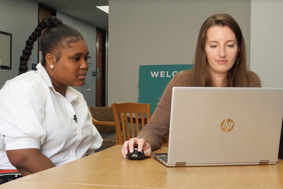 Teacher and student sitting at desk talking