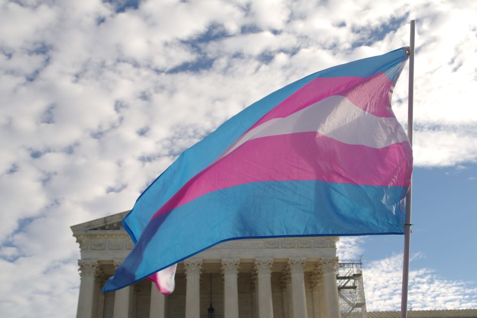 image of the Supreme Court of the United States with a transgender rights flag flying in the foreground