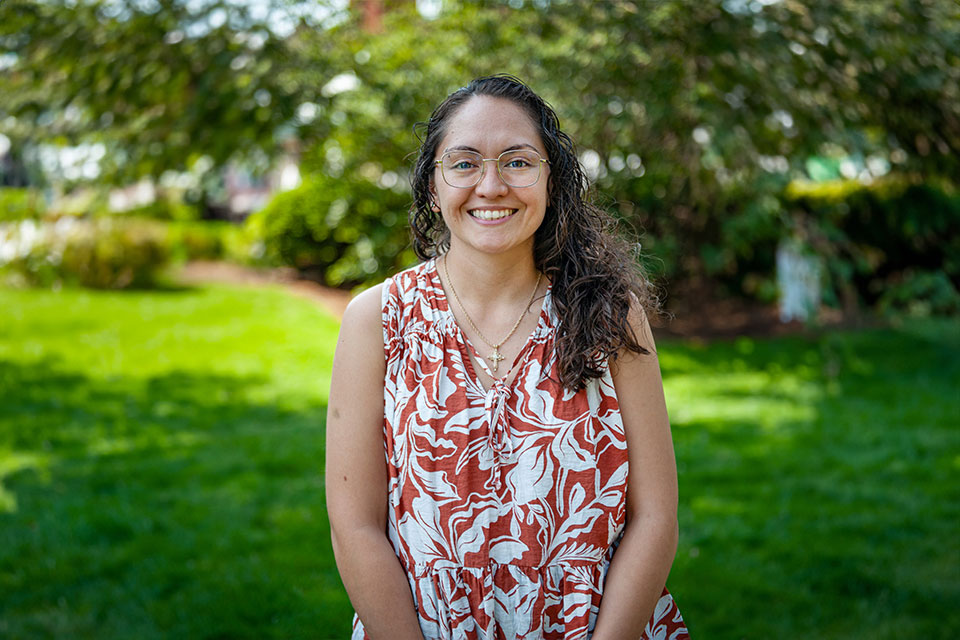 Photograph of Lupe Murillo Wink standing outside in a grassy area with trees in the background