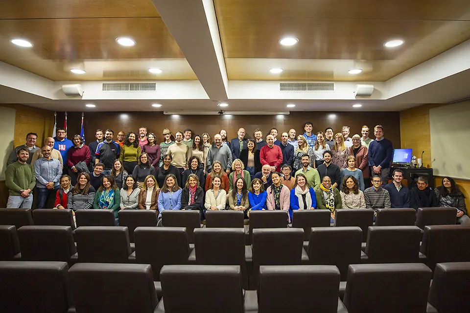 Members of the SLU-Madrid Staff standing and sitting in several rows in an auditorium.