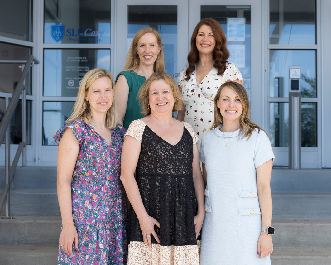 Five faculty members of the dermatopathology program stand in front of a building