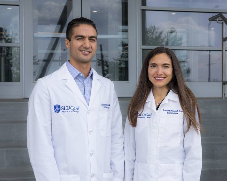 Two faculty members pose outdoors.