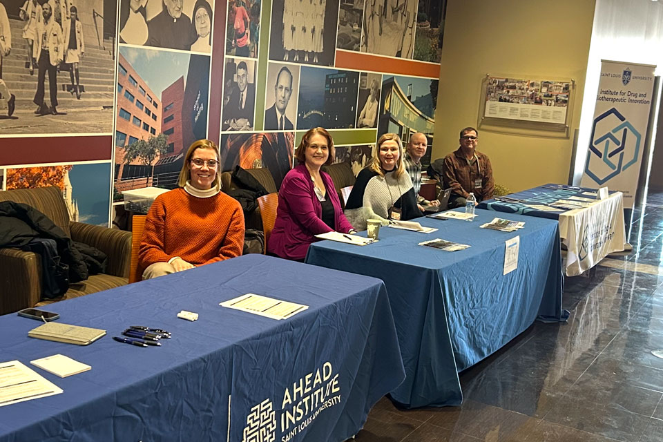 Researchers from the AHEAD Institute and the Institute for Drug and Biotherapeutic Innovation sit at tables available to visit during SLU SOM Science Day. 