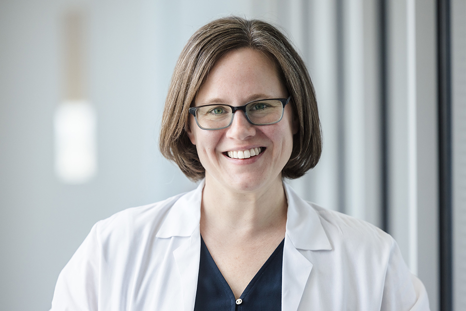 Elise Alspach, Ph.D., poses in her white lab coat for a photo.