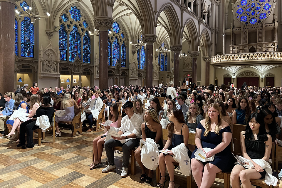 A group of people gather in a church to celebrate SLU's School of Nursing White Coat Ceremony.