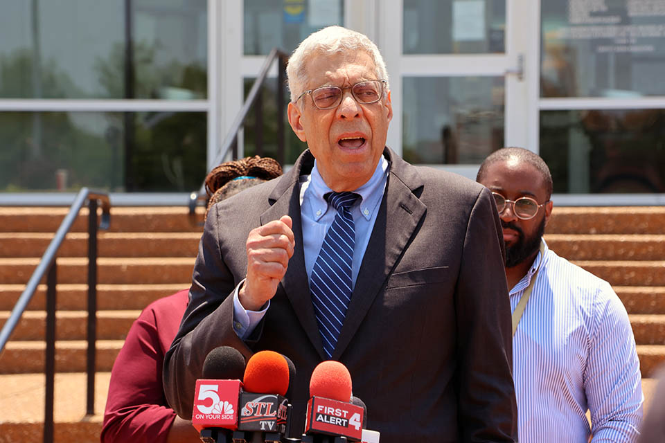 SLU President Fred P. Pestello, Ph.D., speaks at a press conference. Two people stand behind him at the podium.
