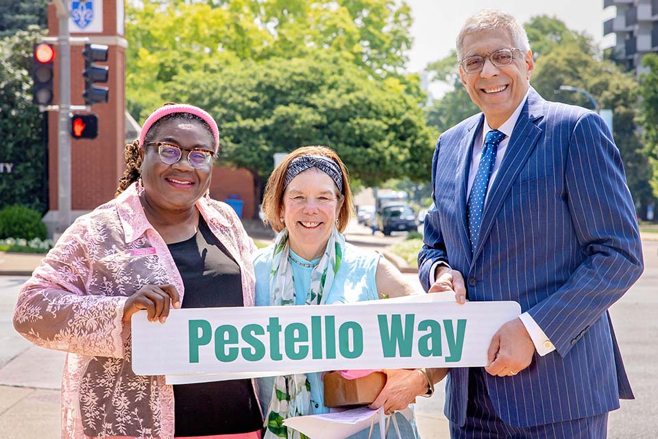 Laura Keys, Ward 11 Alderwoman, First Lady Fran Pestello, Ph.D., and President Fred P. Pestello, Ph.D., pose with a Pestello Way street sign on SLU's north campus on a bright, sunny day.