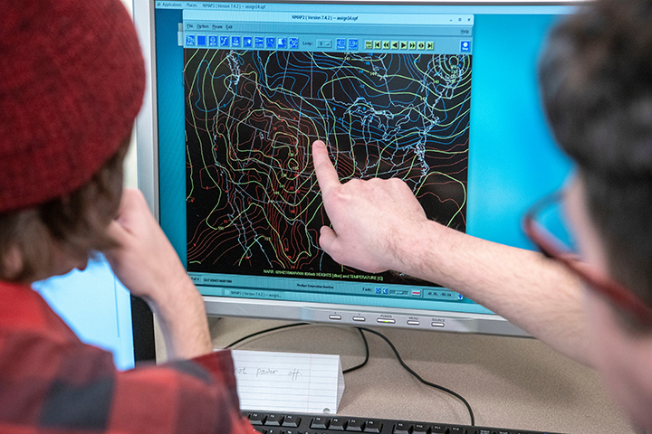 Meterology students looking at a computer screen with weather information